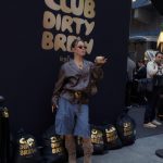 Guest posing at the Club Dirty Brew photo booth with gold coffee sacks
