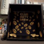 Walk-in photo booth with oversized gold coffee beans and Club Dirty Brew logo