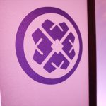Tatcha crest on a lit architectural film panel of the plexiglass tea pavilion