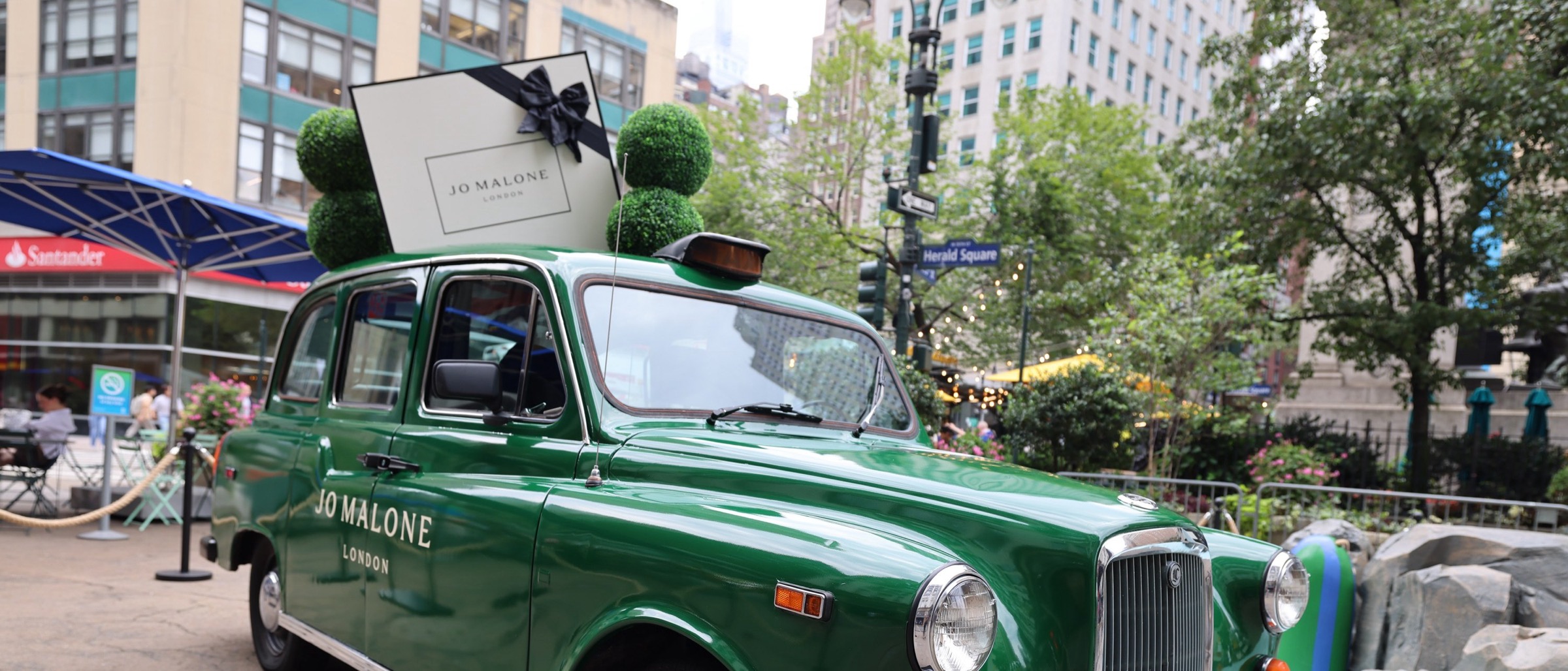 Green London taxi branded for Jo Malone London with giant gift box and topiaries on the roof at Herald Square