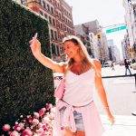 Guest taking a selfie at the pink floral hedge on Broadway