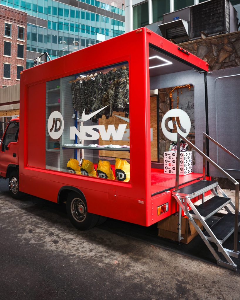 JD x Nike Sportswear glass truck JD × Nike Sportswear glass truck wrapped in red with stairs deployed on a NYC street